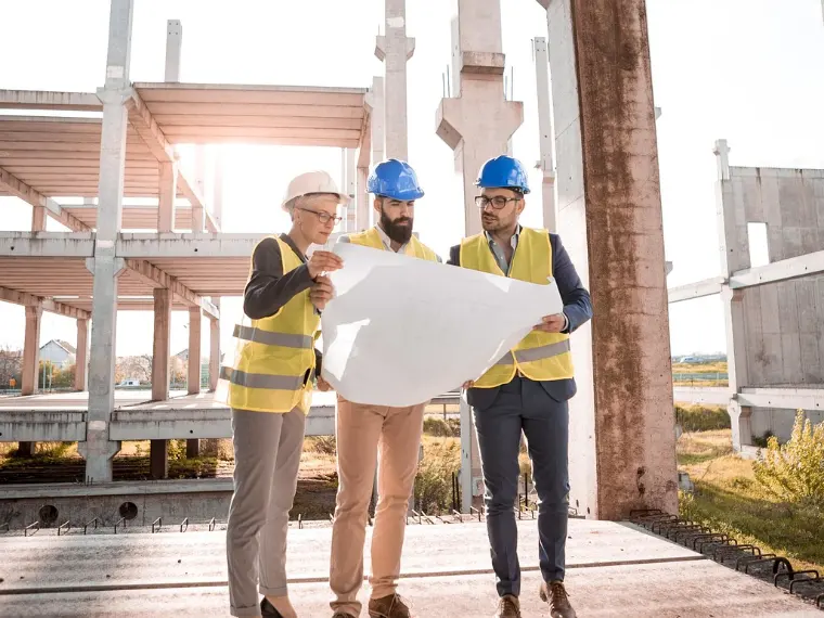 Drei Fachleute besprechen einen Plan auf der Baustelle