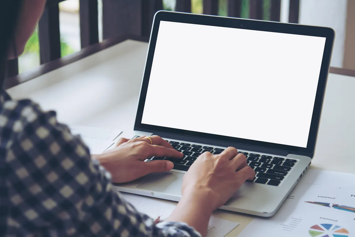 Arbeit am Laptop mit Auswertungen auf dem Schreibtisch